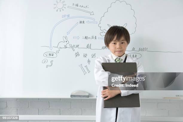 boy (8-9) holding file in front of white board - indeed stock pictures, royalty-free photos & images
