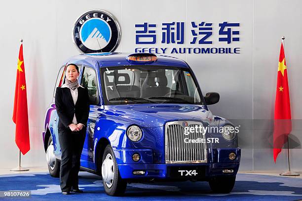 Worker stands beside Geely's version of the London taxis on display at the headoffice building of Chinese carmaker Zhejiang Geely Holding in...