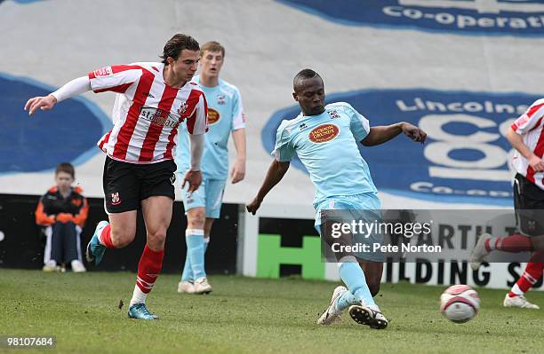 Abdul Osman of Northampton Town plays the ball watched by Davide Somma of Lincoln City during the Coca Cola League Two Match between Lincoln City and...