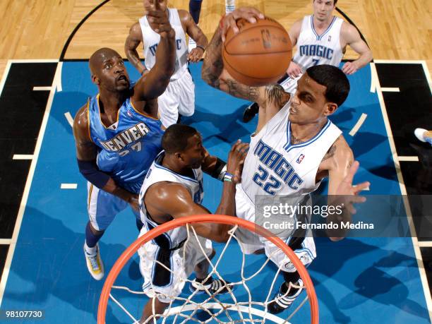 Matt Barnes of the Orlando Magic pulls down a rebound against Johan Petro of the Denver Nuggets during the game on March 28, 2010 at Amway Arena in...
