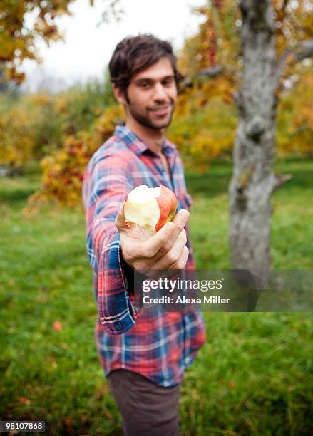 man offering apple to camera. - croquant photos et images de collection