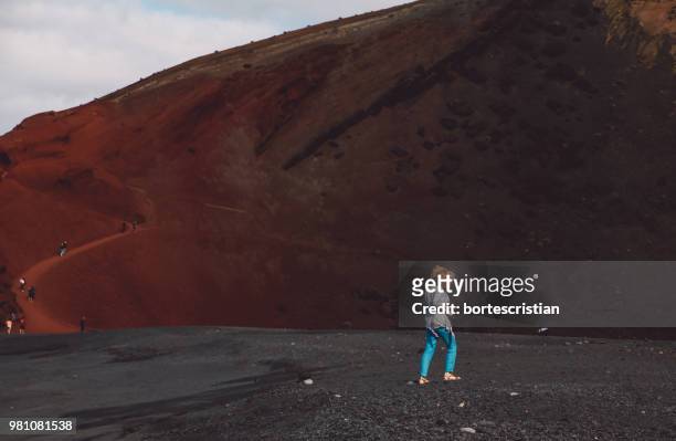 full length of woman walking on road against mountains - bortes photos et images de collection