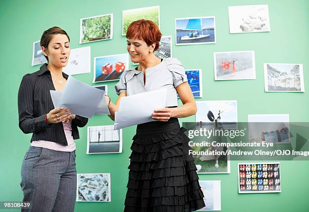 two woman talking to each other with paperwork - older women in short skirts stock pictures, royalty-free photos & images