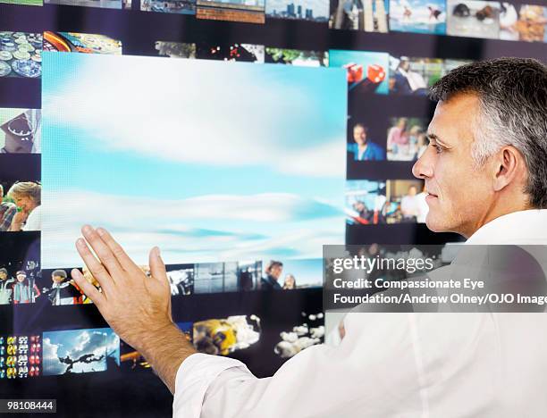 grey haired man using a digital display - vista trasera de tres cuartos fotografías e imágenes de stock