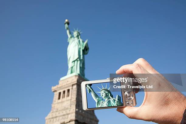 tourist taking picture of statue of liberty - travelpix stock pictures, royalty-free photos & images