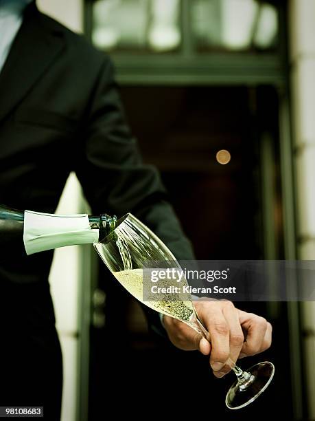 waiter pouring champagne into champagne flute - champagner gläser mit flasche unscharfer hintergrund stock-fotos und bilder