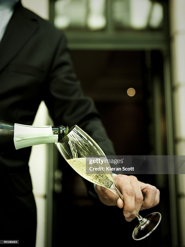 Waiter pouring champagne into champagne flute