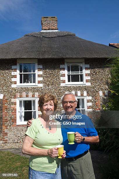 senior couple in garden of country cottage - newpremiumuk stockfoto's en -beelden