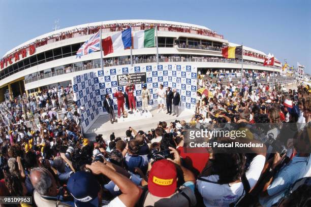 Alain Prost, driver of the Marlboro McLaren-Honda MP4/5 stands on the podium with second placed Nigel Mansell and third placed Riccardo Patrese as...