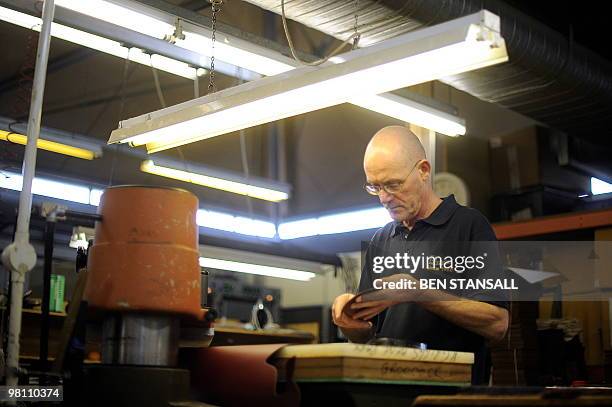 Dr Martens employee works on a boot in the Dr Martens factory in Wellingborough, Northamptonshire, in central England, on March 18, 2010. What do...