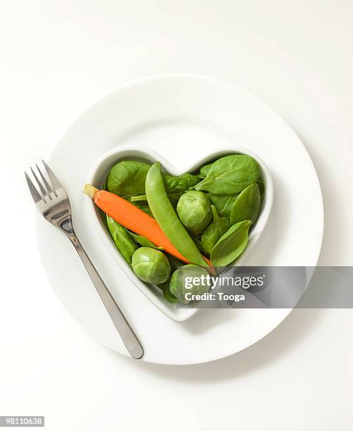 heart shaped bowl of vegetables - ベビーキャロット ストックフォトと画像