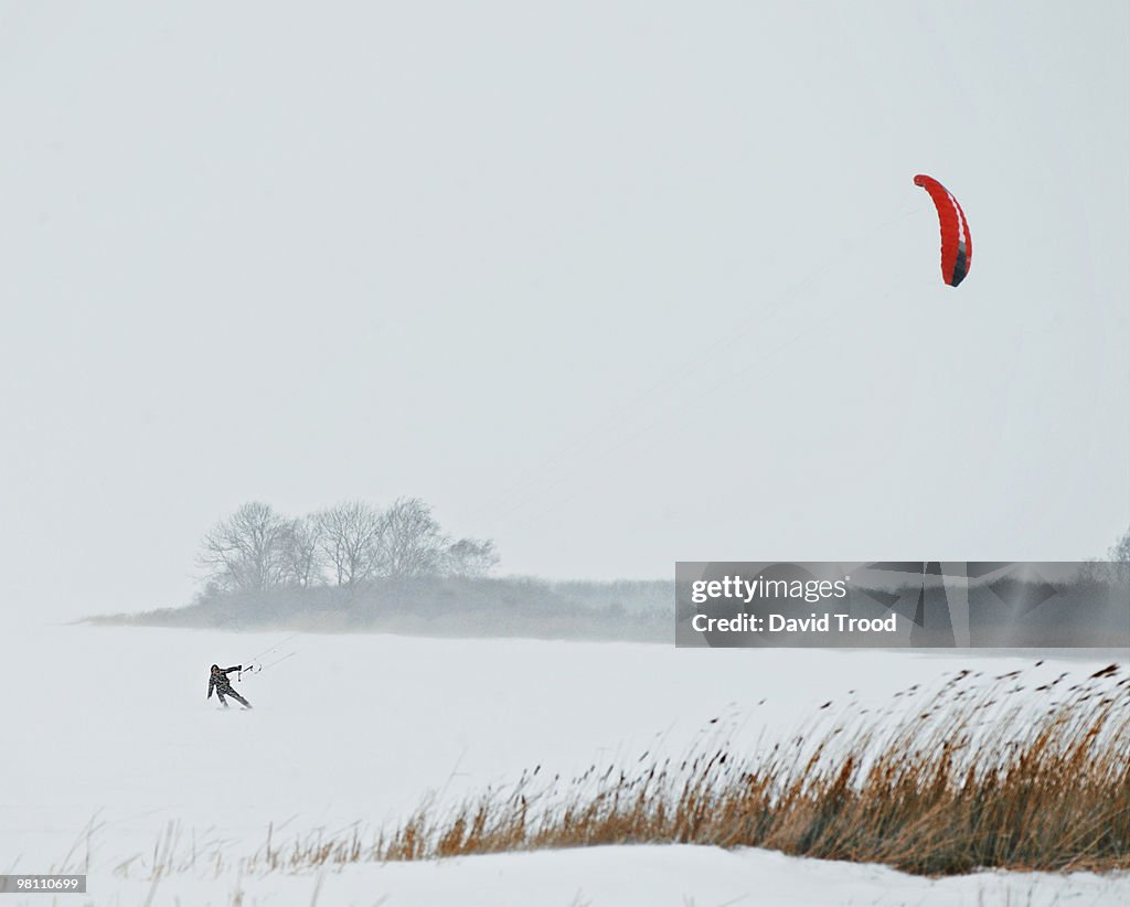 Man kite boarding in a snowstorm