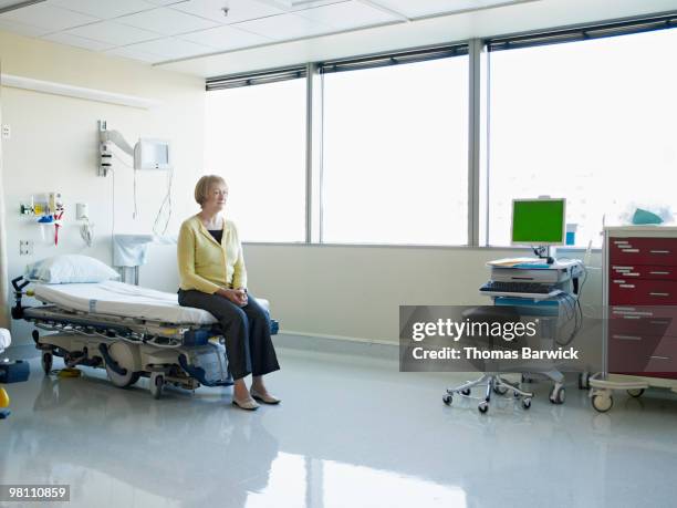 mature patient sitting on gurney in hospital suite - hospital gurney stock pictures, royalty-free photos & images