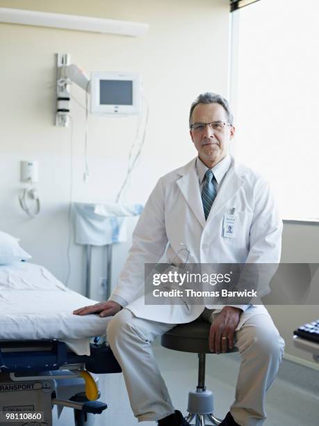 doctor sitting next to gurney in hospital room - doctor sitting stock pictures, royalty-free photos & images