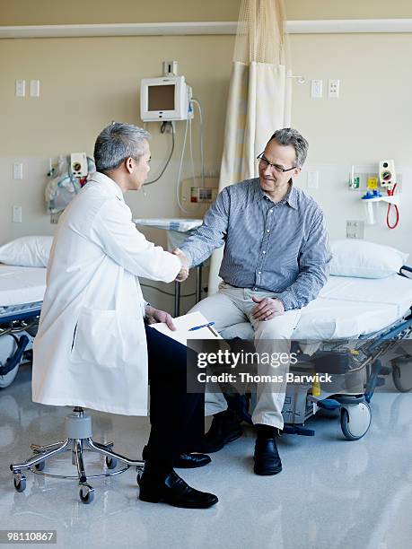 doctor and patient shaking hands in hospital suite - asian man suite stock-fotos und bilder