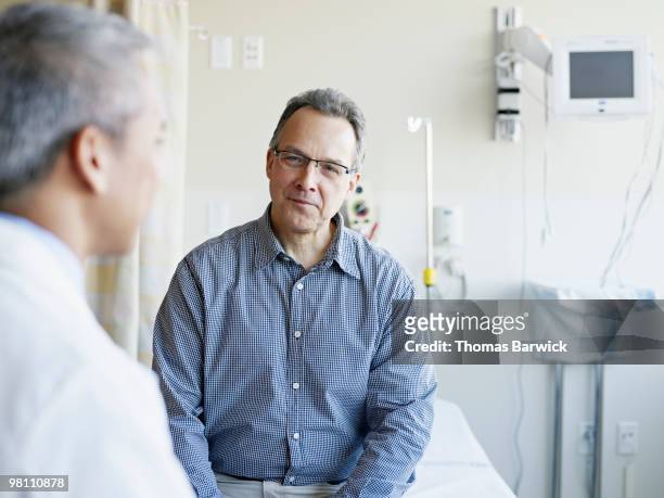 doctor talking to patient in hospital room - doctor and patient talking fotografías e imágenes de stock