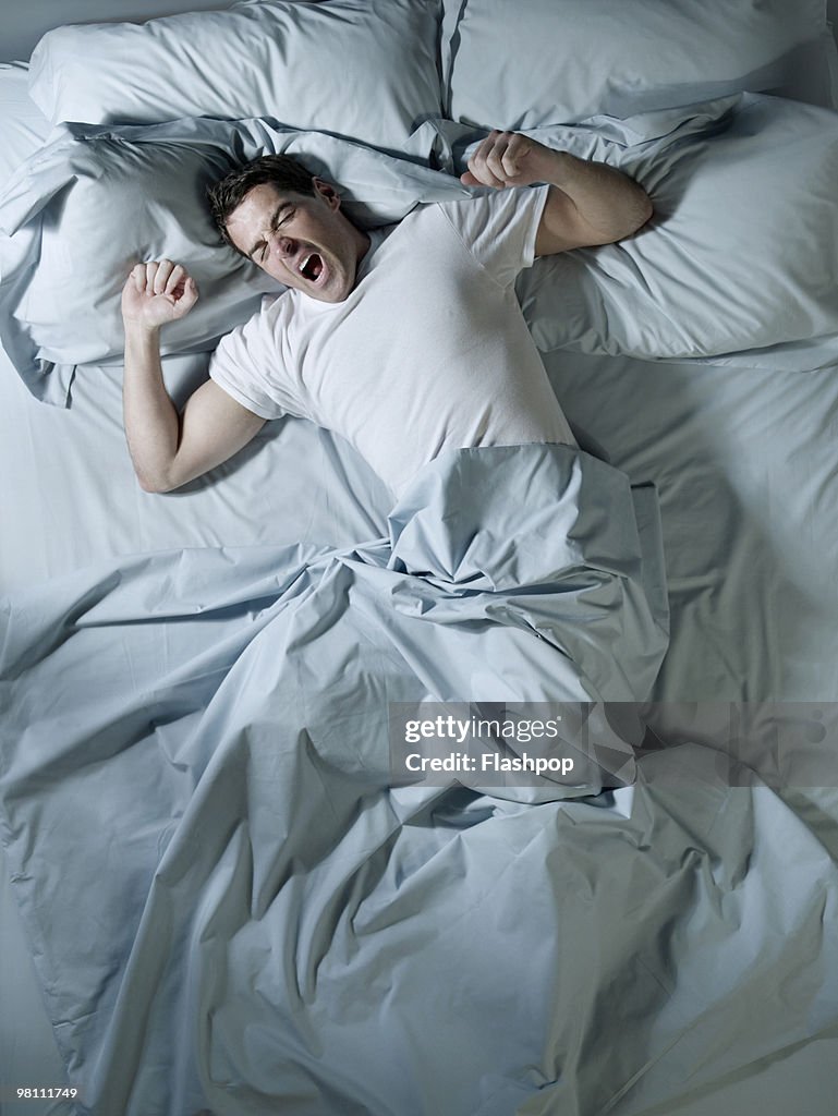 Man stretching and yawning in bed