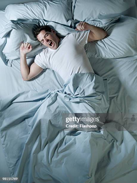 man stretching and yawning in bed - bed overhead stock pictures, royalty-free photos & images