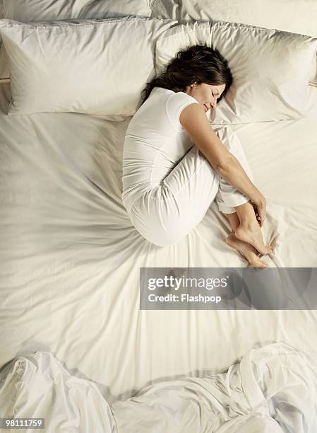 woman sleeping in bed - position du foetus photos et images de collection