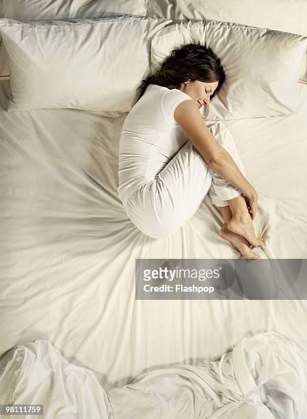 woman sleeping in bed - hugging knees - fotografias e filmes do acervo