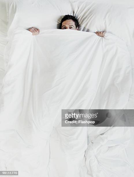 man peering over the top of bed sheet - alleen één man stockfoto's en -beelden