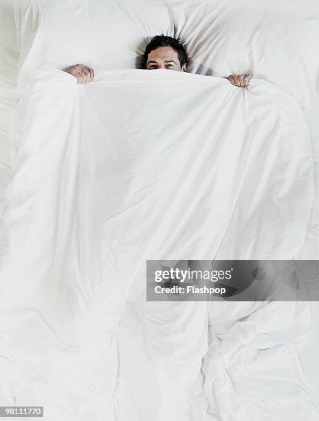 man peering over the top of bed sheet - endast en man bildbanksfoton och bilder