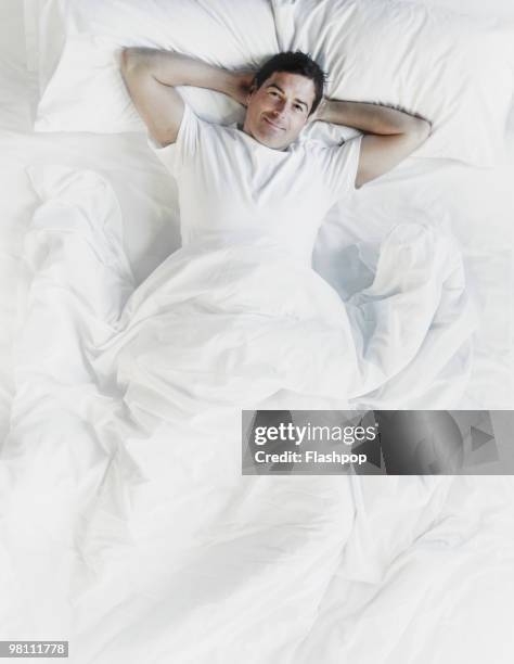 man relaxing in bed - bed above stock pictures, royalty-free photos & images