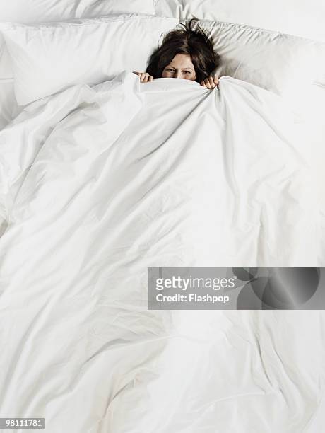 woman peering over the top of bed sheet - quilt imagens e fotografias de stock