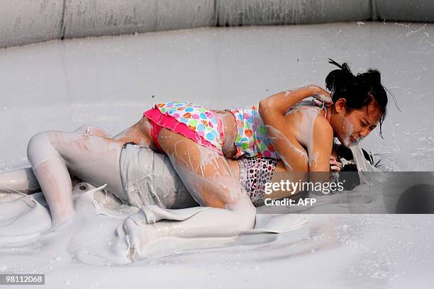Two Chinese women wrestle in a mud pool during an international women's mud wrestling contest held in Haikou, south China's Hainan island on March...