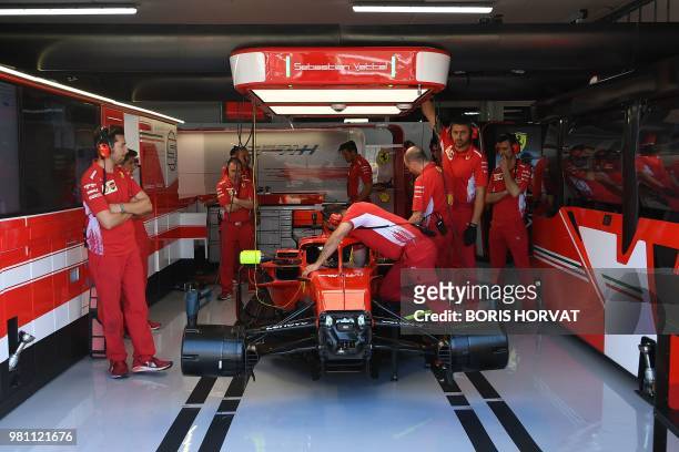 Technicians work on the car of Ferrari's German driver Sebastian Vettel in the pits ahead of the first practice session at the Circuit Paul Ricard in...