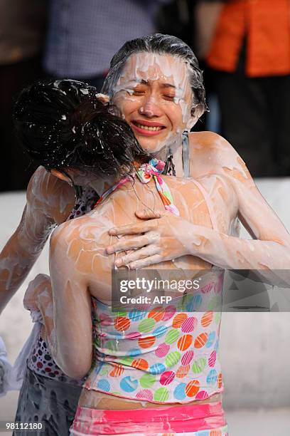 Two Chinese women embrace after a mud wrestling bout during an international women's mud wrestling contest held in Haikou, south China's Hainan...