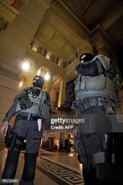 Masked and armed policemen stand guard in Brussel's justice palace as extra security measures are taken on March 29 at the trial in Brussels criminal...