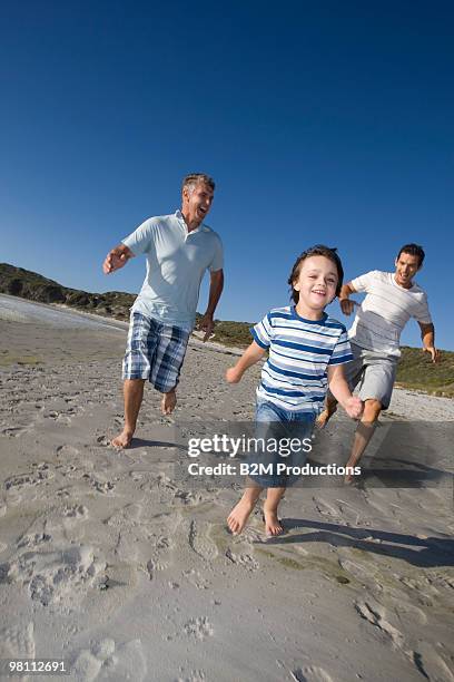 grandfather, father and son (4-5) running on beach - 45 49 år bildbanksfoton och bilder
