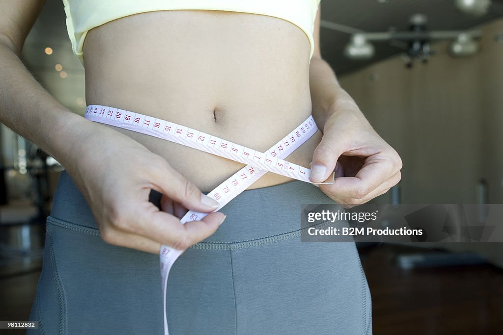Young woman measuring stomach
