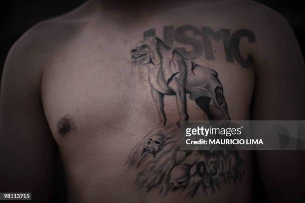 3rd Battalion, 6th Marines, Sergeant Paul Williams of Fostoria, Ohio, poses to show his chest tattoo with the inscription USMC and a bull dog , for a...