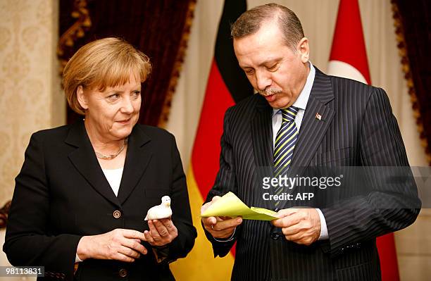 German Chancellor Angela Merkel presents a white dove figurine to Turkey's Prime Minister Recep Tayyip Erdogan during a meeting in Ankara on March...