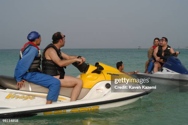 Two couples on jet-skis in Kish, a resort island in the Persian Gulf, Iran, 3rd July 2003. The women are wearing the special wetsuits which are...