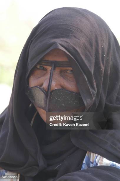 Native woman in traditional dress with a niqab covering her face, seen in the old town of Kish, a resort island in the Persian Gulf, Iran, 3rd July...