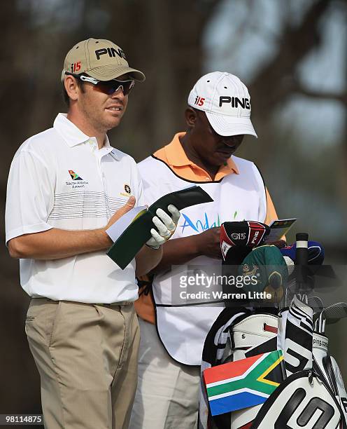 Louis Oosthuizen of South Africa checks his yardage as his bag sports a South African flag during the fourth round of the Open de Andalucia 2010 at...