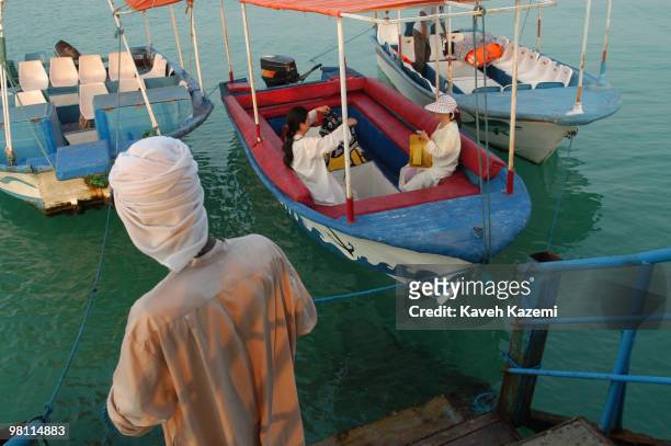 Native man moors a boat with two Asian tourists on board in Kish, a resort island in the Persian Gulf, Iran, 3rd July 2003.