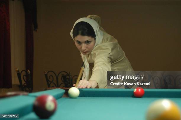 Young woman in a veil plays pool in a hotel entertainment hall in Kish, a resort island in the Persian Gulf, Iran, 4th July 2003. Women are not...