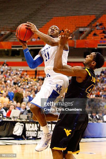 John Wall of the Kentucky Wildcats drives for a shot attempt against Joh Flowers of the West Virginia Mountaineers during the east regional final of...