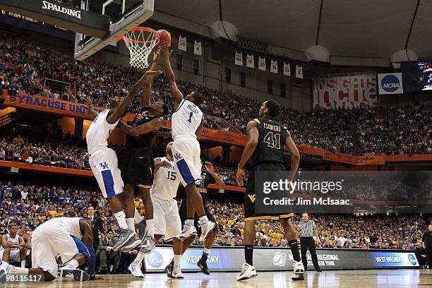 Devin Ebanks of the West Virginia Mountaineers reaches for a rebound against DeAndre Liggins and Darius Miller of the Kentucky Wildcats during the...