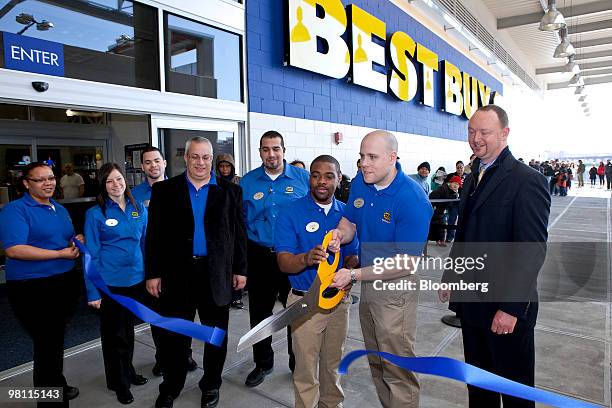 Best Buy managers Brian Placek, center right, and Clarence Cobb, center left, cut a ceremonial ribbon during the opening of a new Best Buy store in...