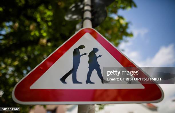 Picture taken on April 25, 2018 shows a modified caution sign warning against so-called "smombies", people watching their smartphones, in a street...