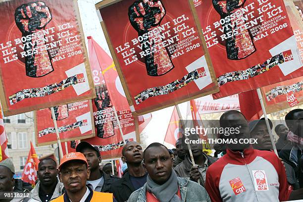 People hold placards, reading : "They work here, they live here, they stay here" in support of illegal workers during a demonstration on March 23,...