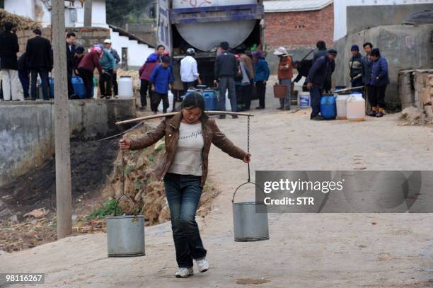 Villagers collect water from a truck which delivers the daily supply of water to Qujing, in southwest China's Yunnan province on March 26 after...