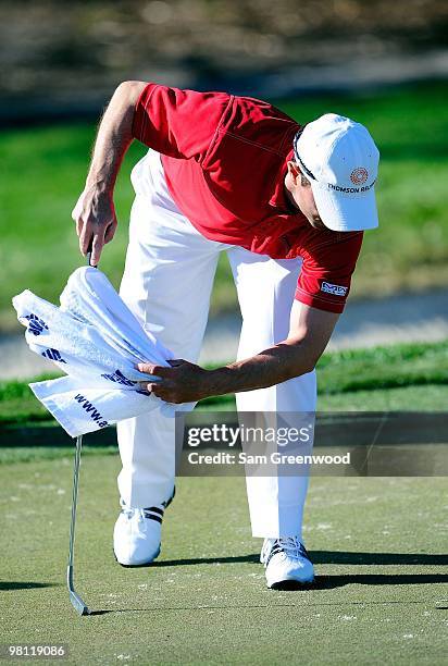Mike Weir of Canada sweeps sand from the green during the first round of the Honda Classic at PGA National Resort And Spa on March 4, 2010 in Palm...
