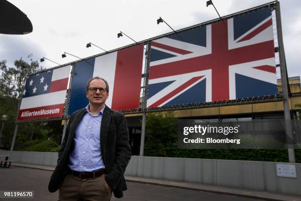 Florian Weiss, curator at the Allied Museum, poses for a photograph back-dropped by the U.S., France and United Kingdom national flags following an...