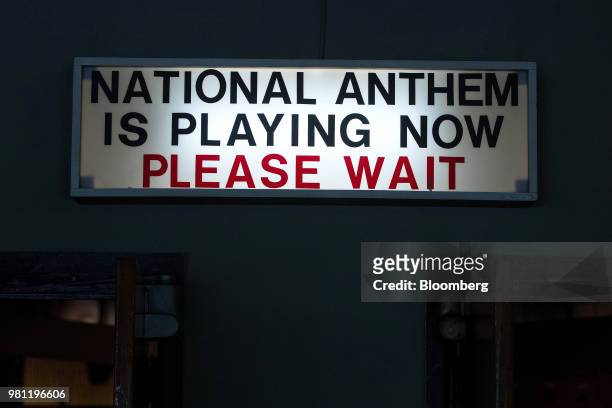 Movie theater sign reading 'National Anthem Is Playing Now Please Wait' sits illuminated at the American Outpost exhibition inside the Allied Museum...
